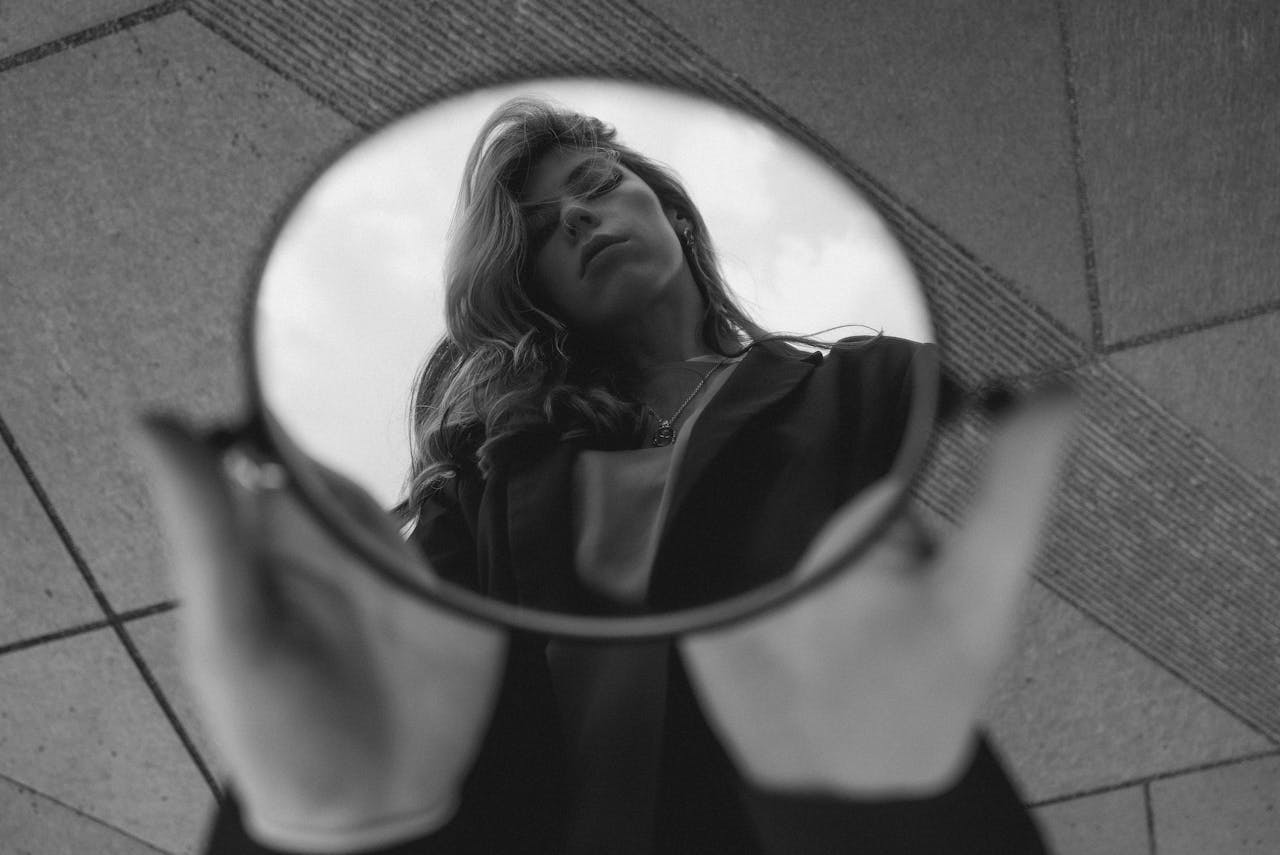 Black and white artistic photo of a woman reflected in a round mirror outdoors in Berlin.