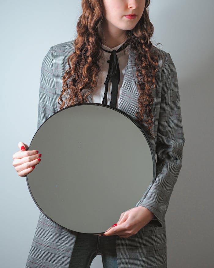 Stylish woman in Paris holding a round mirror, capturing elegance and modern fashion.